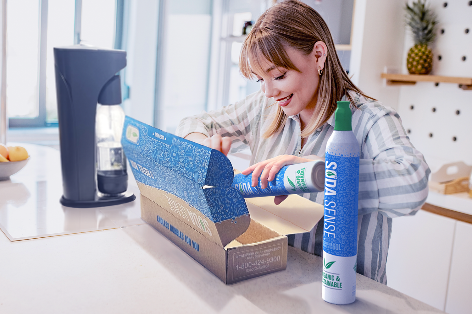 A smiling woman places a threaded Soda Sense CO2 refill canister into a refill box on a kitchen counter, with a soda maker in the background.